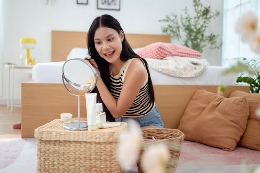 Woman following her summer skincare routine while looking into a tabletop mirror at home