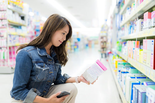Woman browsing supplement products on a store shelf while comparing options for her summer wellness routine