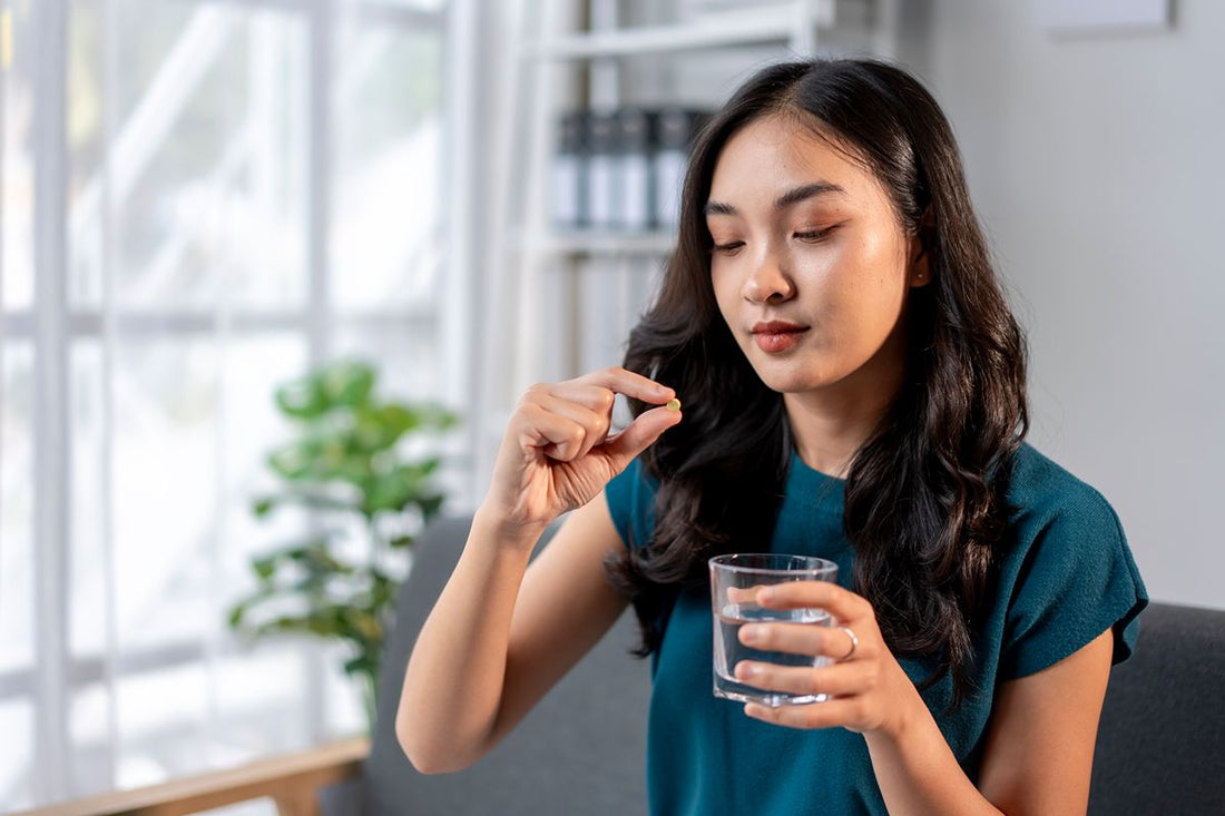 Woman taking a supplement with a glass of water as part of her daily wellness routine
