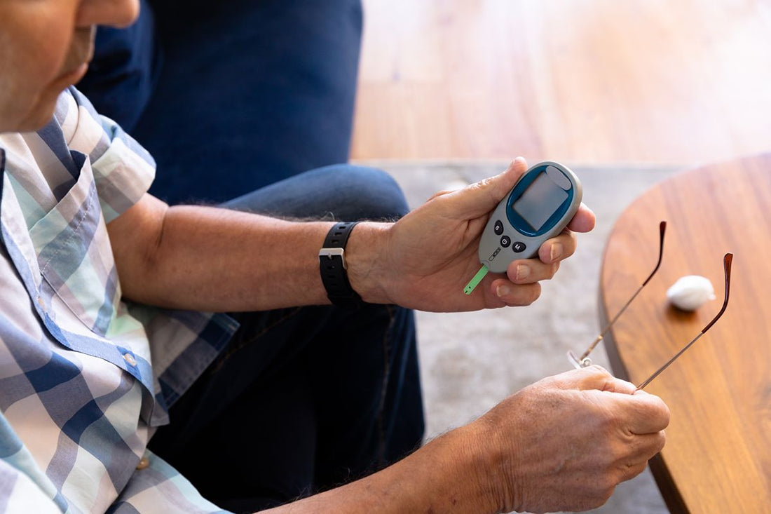 Older man checking his blood sugar with a glucose meter while seated at home