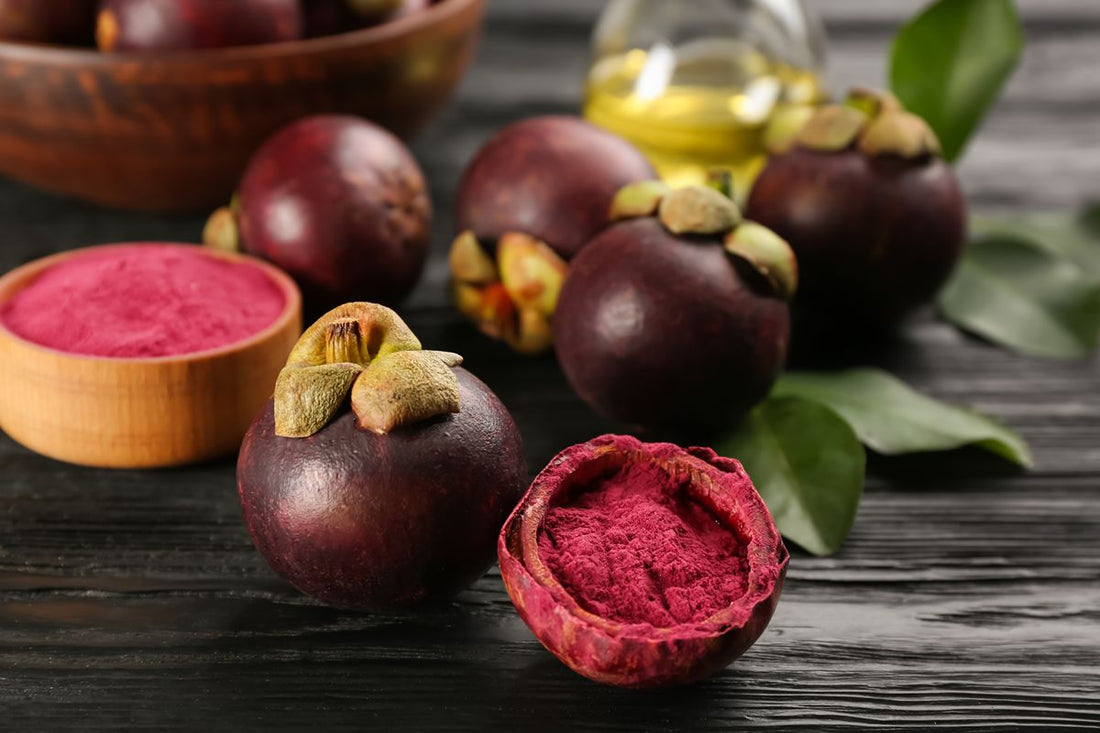 Fresh whole and cut mangosteen fruits displayed on a dark wooden surface