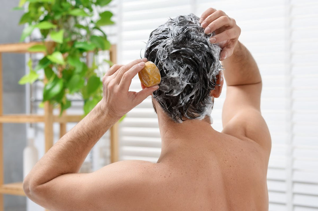 Man washing his hair and scalp with a bar soap during a shower