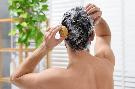 Man washing his hair and scalp with a bar soap during a shower