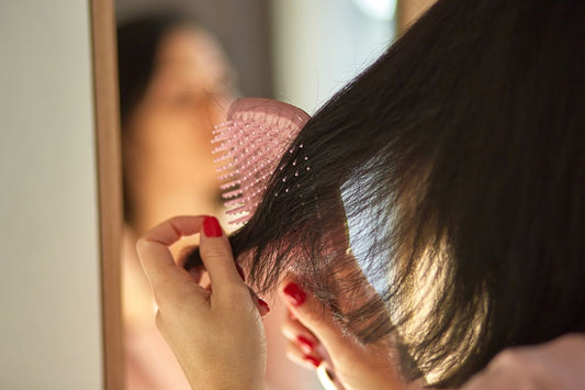 Babaeng sinusuri ang kanyang buhok habang may hawak na hairbrush dahil sa concern sa hair fall